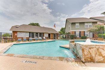 A swimming pool with a slide and a house in the background.